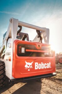 Bobcat skid steer loader parked outdoors with clear sky and sunny backdrop, showcasing heavy machinery design.